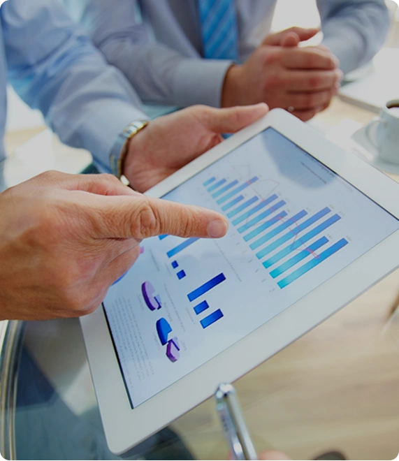 Jemand zeigt einer anderen Person etwas auf einem Tablet. Darauf sind unterschiedliche Balkendiagramme zu sehen