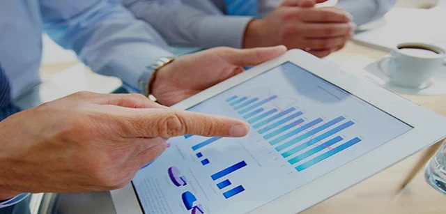 Mann zeigt auf ein Balekndiagramm auf einem Tablet, das er in der Hand hält